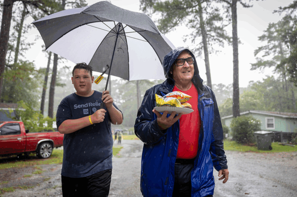 wo Send Relief volunteers walk through the rain delivering hot meals during a Serve Tour outreach